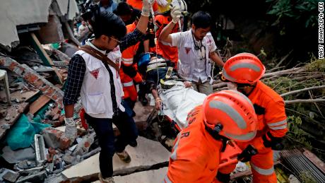 redders verplaatsen een overlevende uit een ingestort restaurantgebouw in Palu.