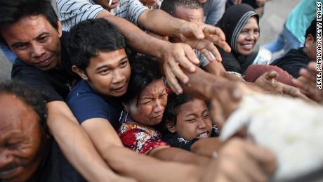 Survivors scuffle for live chickens being distributed from a police truck in Palu on October 2.