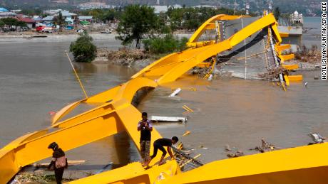 lidé zkoumají trosky mostu poblíž pláže Talise v Palu.