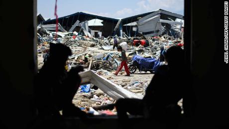 sobreviventes do tremor salvam itens dos destroços de um complexo de fábrica em Palu.