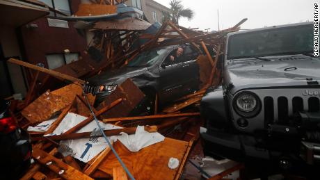 A storm chaser tries to get equipment from a vehicle after a hotel canopy fell in Panama City Beach. 