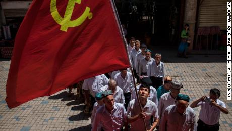 Ethnic Uyghur members of the Communist Party of China carry a flag as they take part in an organized tour on June 30, 2017 in the old town of Kashgar, in the far western Xinjiang province, China.