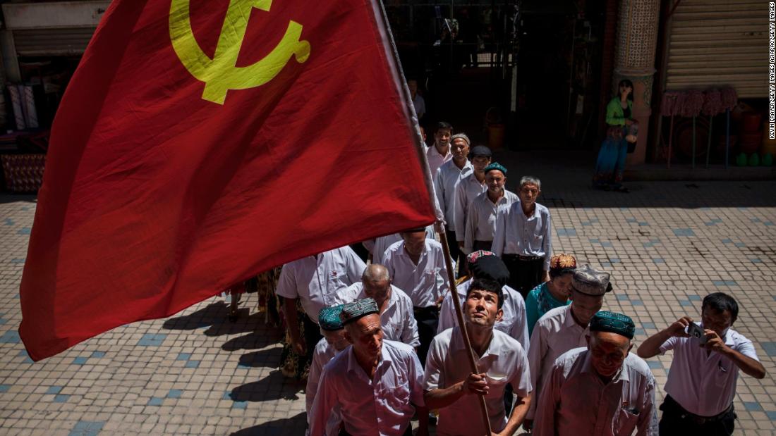 Ethnic Uyghur members of the Communist Party of China carry a flag as they take part in an organized tour on June 30, 2017 in the old town of Kashgar, in the far western Xinjiang province, China.