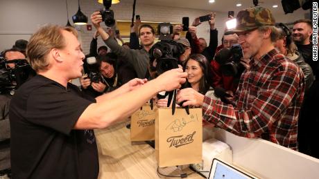 Canopy Growth CEO Bruce Linton hands Ian Power, who is first in line to purchase the first legal recreational marijuana after midnight, his purchases at a Tweed retail store in St John&#39;s, Newfoundland and Labrador, Canada October 17, 2018.  REUTERS/Chris Wattie