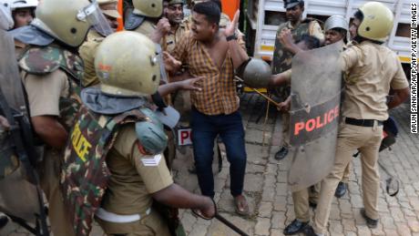 Police take a Hindu activist into custody as protesters rally against the Supreme Court verdict.