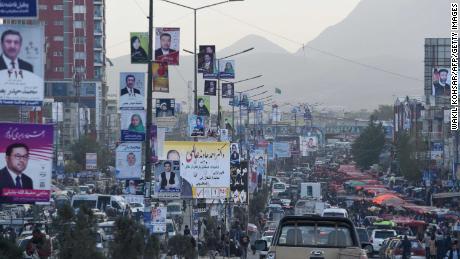 Kabul commuters drive past posters of candidates Monday during the legislative election campaign.