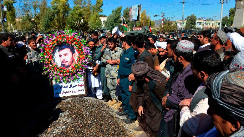 Civilians and military personnel stand beside the grave of Gen. Abdul Raziq, Kandahar police chief, during his burial in Kandahar on Friday.