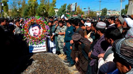 Civilians and military personnel stand beside the grave of Gen. Abdul Raziq, Kandahar police chief, during his burial in Kandahar on Friday.