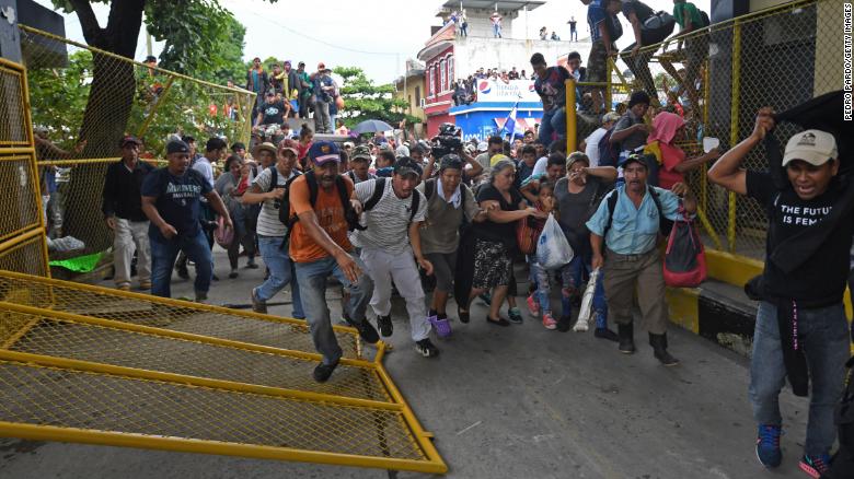 Honduran migrants heading in a caravan to the US rush through the Guatemala-Mexico international border bridge after tearing down its gate in Ciudad Hidalgo, Chiapas state, Mexico, on October 19, 2018. - Honduran migrants who have made their way through Central America were gathering at Guatemala's northern border with Mexico on Friday, despite President Donald Trump's threat to deploy the military to stop them entering the United States. 
