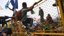 Honduran migrants heading in a caravan to the US climb the gate of the Guatemala-Mexico international border bridge in Ciudad Hidalgo, Chiapas state, Mexico, on October 19, 2018. - Honduran migrants who have made their way through Central America were gathering at Guatemala's northern border with Mexico on Friday, despite President Donald Trump's threat to deploy the military to stop them entering the United States. 