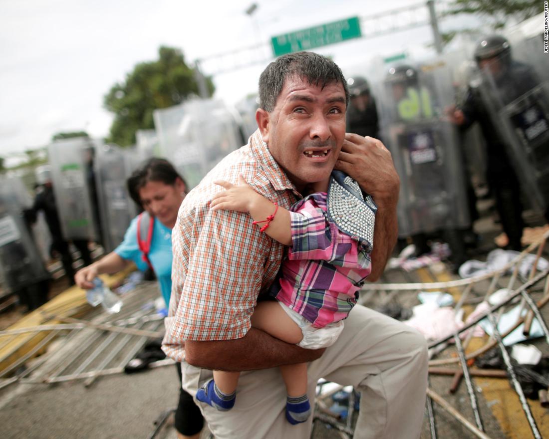 A Honduran man protects his child after fellow migrants, part of a caravan trying to reach the United States, stormed a border checkpoint in Guatemala, in Ciudad Hidalgo, Mexico, Friday, October 19.