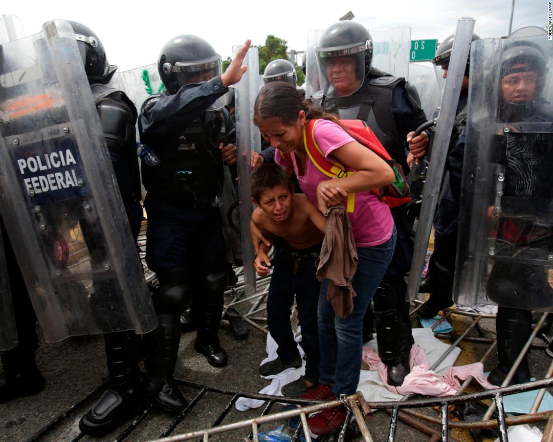 A Honduran migrant mother and child are surrounded by Mexican Federal Police in riot gear, at the border crossing in Ciudad Hidalgo, Mexico, Friday, October 19. 