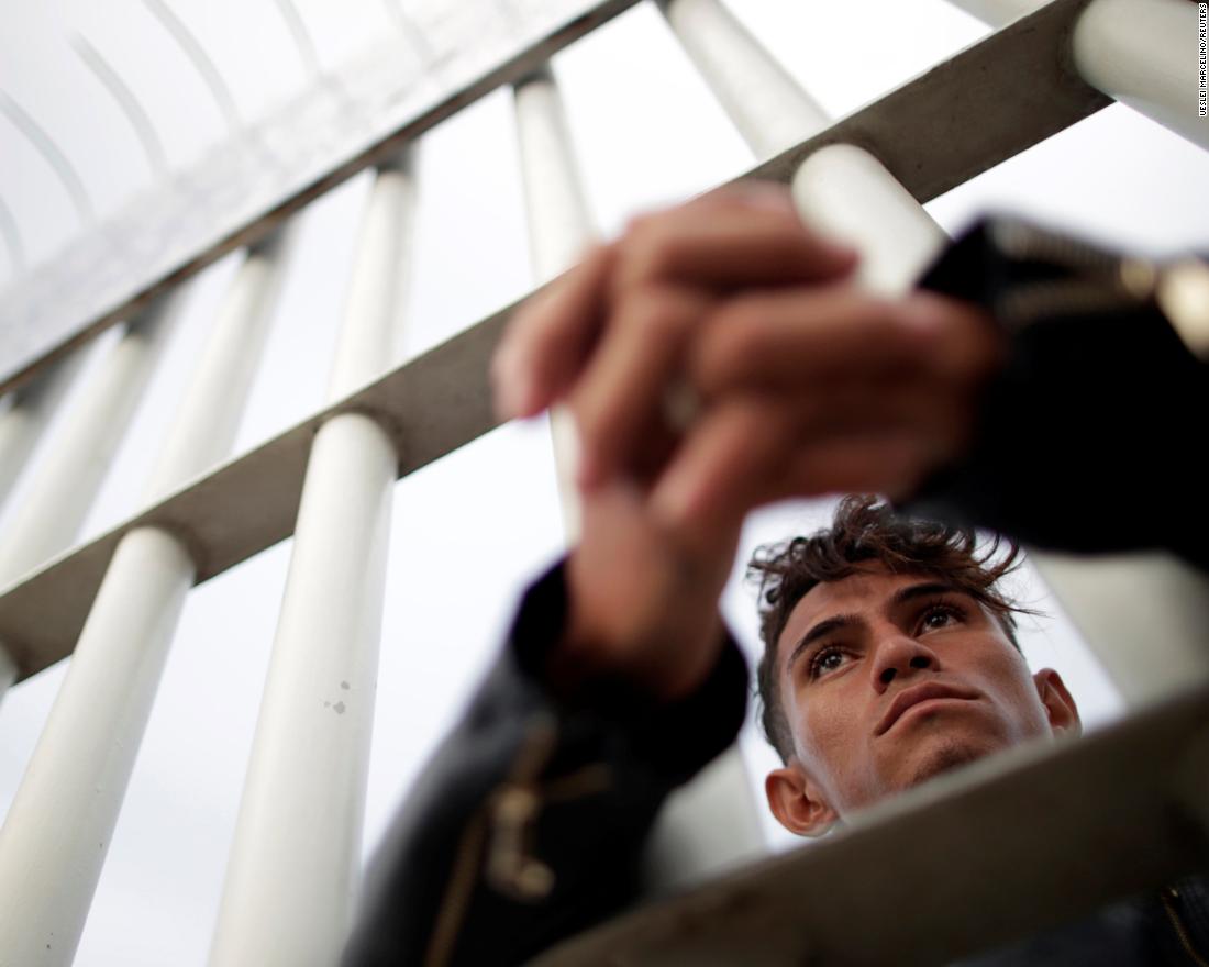 A Honduran migrant looks through the gate on the bridge that connects Mexico and Guatemala in Tecun Uman, Guatemala, on Saturday.