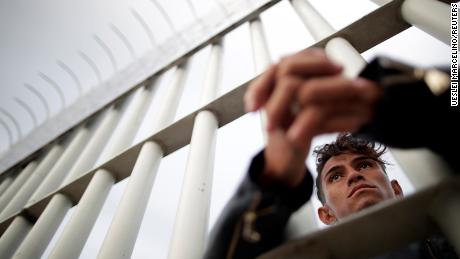 A Honduran migrant looks out from a gate on a bridge connecting Mexico and Guatemala in Tecun Uman, Guatemala. 