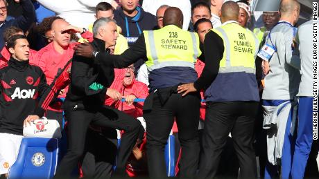 Stewards hold back Jose Mourinho as he clashes with the Chelsea backroom staff during Saturday's Premier League match.