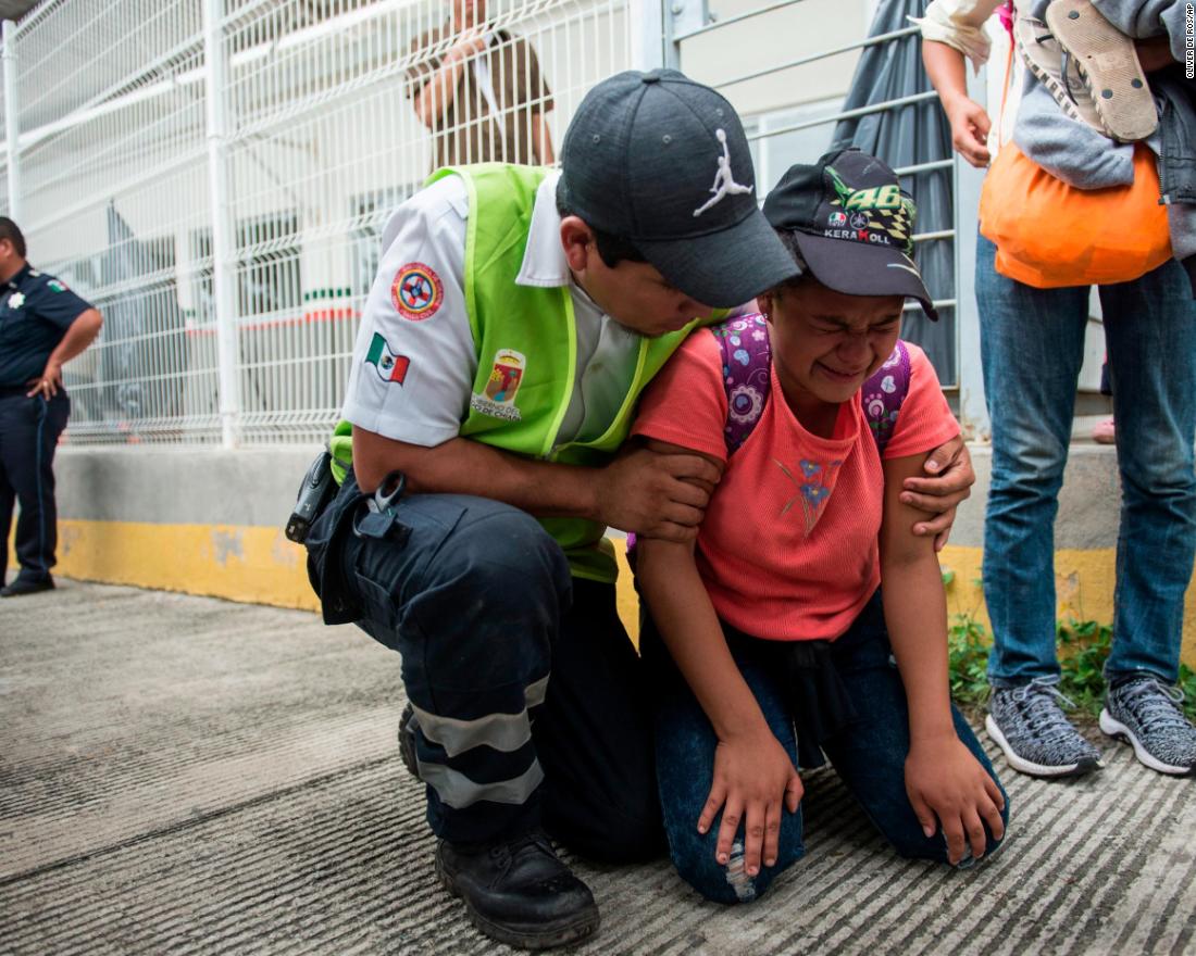 A migrant is comforted by a Mexican paramedic after her mother fainted while crossing the border between Guatemala and Mexico.