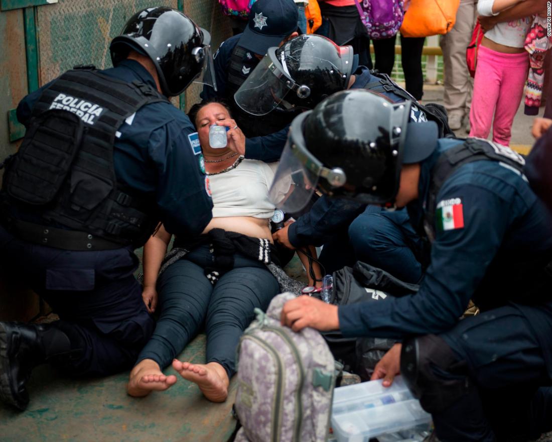 Mexican paramedics help a Honduran woman who fainted after crossing the border between Guatemala and Mexico on Saturday.