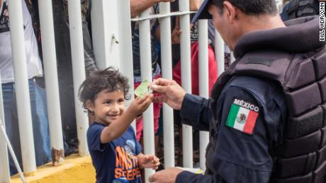 A young boy named Carlitos plays with a Mexican federal police officer as he waits with his mom on the bridge from Guatemala.