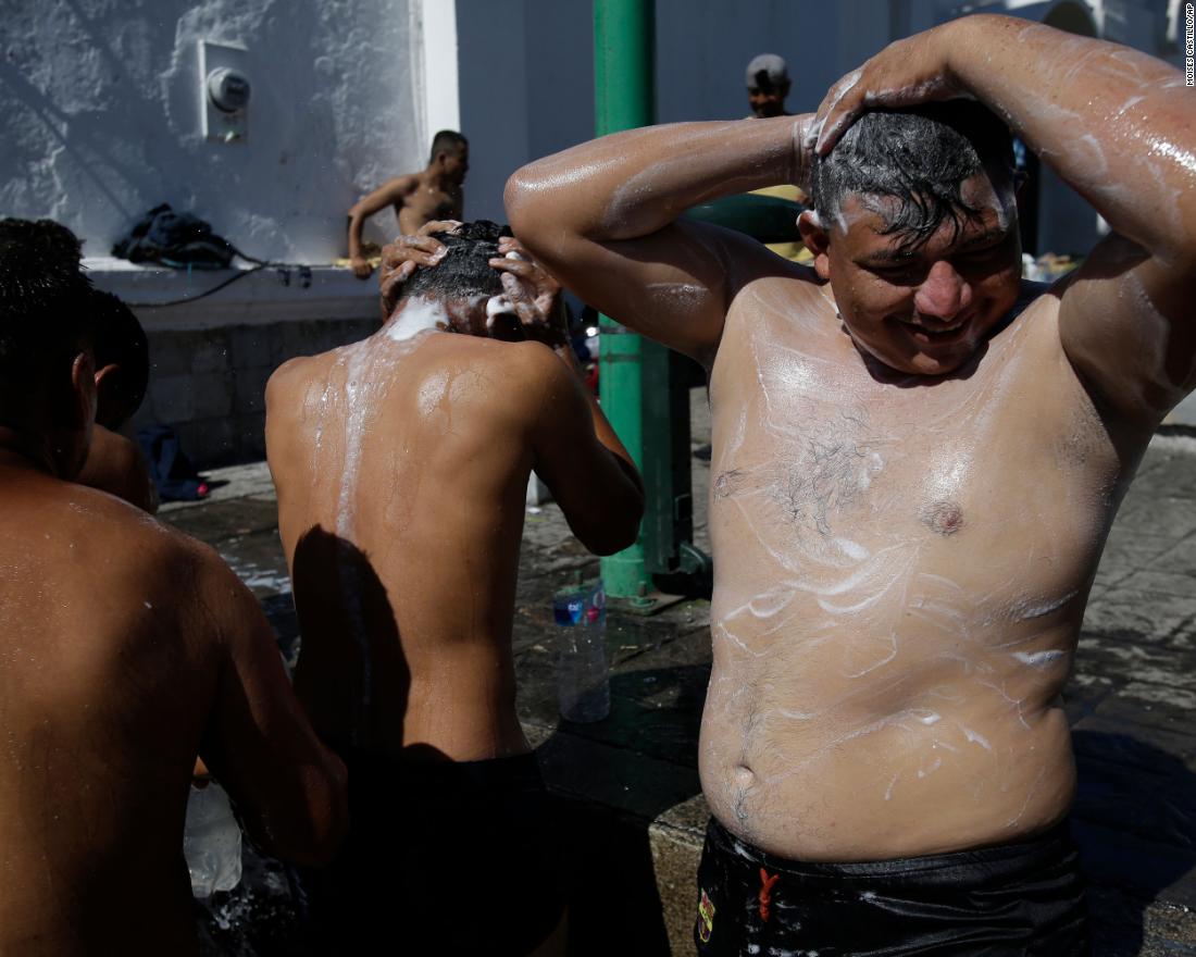 Migrant men bathe using water from a fire hydrant at the main plaza in Tapachula, Mexico. 