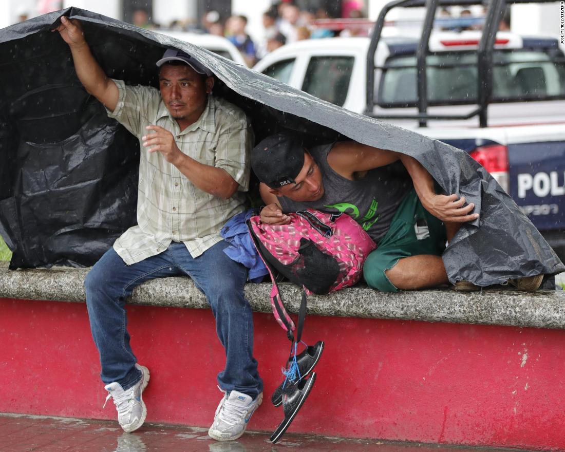 Migrants take shelter from the weather under a tarp as they rest in the town of Huixtla, Mexico, on October 22.