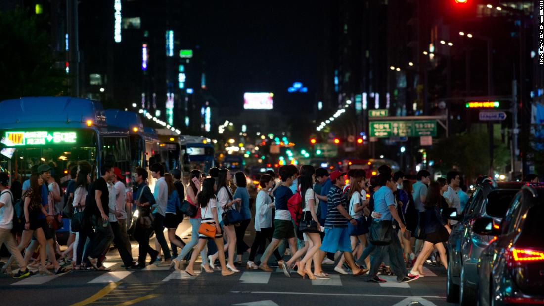 Pedestrians cross a road in the Gangnam district of Seoul. South Korea has some of the longest working hours in the world. 