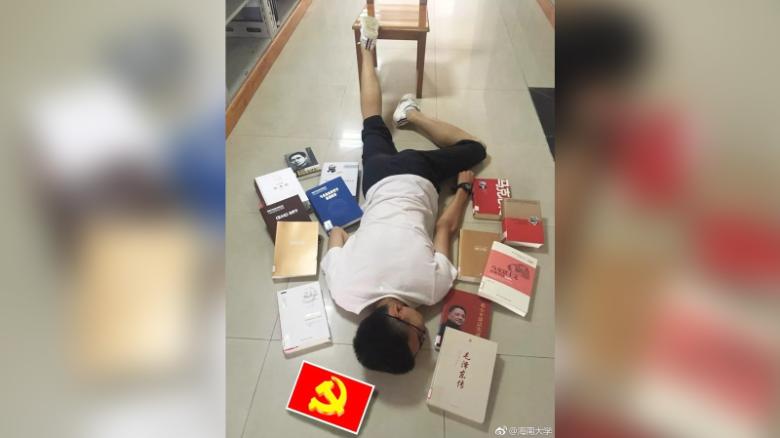 A student at Hainan University lies among his text books, including works about Karl Marx, Mao Zedong and Deng Xiaoping