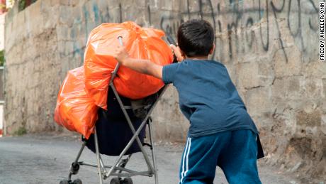 A boy pushes his trash up the road in Jabel Mukaber.