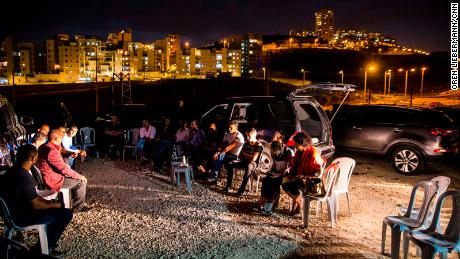 A group of local residents listens to Ramadan Dabash in Um Tuba, with the lights of Har Homa in the background. 