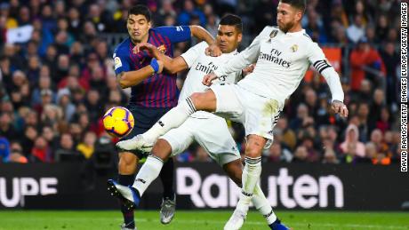 Barcelona's Luis Suarez competes for the ball with Real's Carlos Enrique Casimiro and Sergio Ramos.