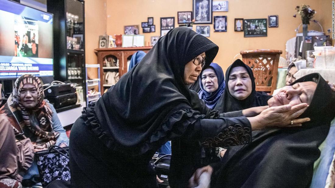 Merdiana Harahap is consoled in Medan, Indonesia. Her husband was on the plane.