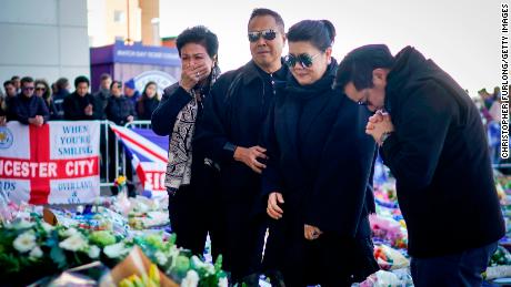 The son and wife ofVichai Srivaddhanaprabha  pray after laying wreathes outside the stadium