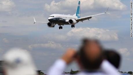 Visitors watch as a Boeing 737 Max lands after an air display during the Farnborough Airshow, south west of London, on July 16, 2018.