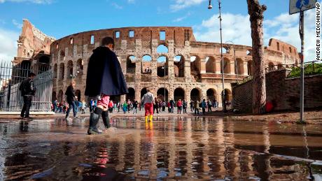 Children play in a puddle by the ancient Colosseum in Rome on Tuesday, a day after strong winds and rain hit the city.