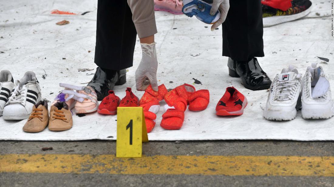 A police officer arranges shoes recovered during search operations.