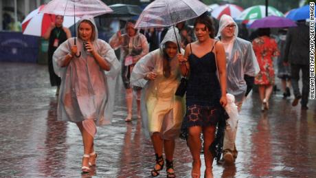 Race-goers take shelter from the rain ahead of the Melbourne Cup.