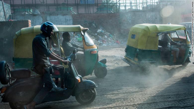 Auto rickshaw drivers pass a building site in Old Delhi. 