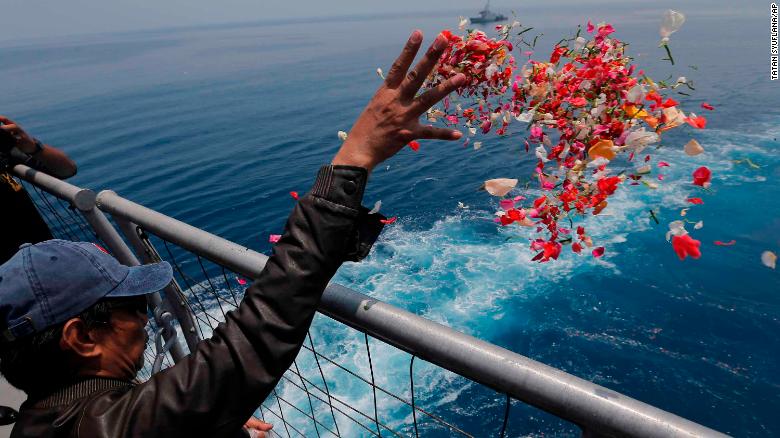 A relative of one of the crash victims tosses flower petals from an Indonesian Navy ship on Tuesday, November 6.