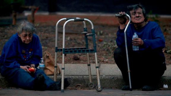 Juanita and Wayne McLish sit on a curb November 8 after losing their house to the Camp Fire in Paradise.