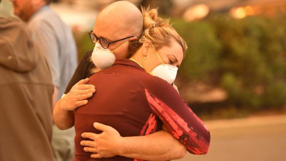 People embrace in the parking lot of a Paradise hospital as the Camp Fire engulfed it on November 8.