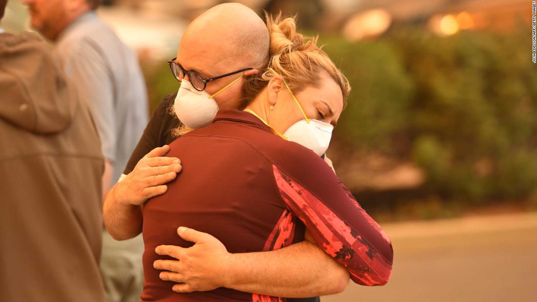 People embrace in the parking lot of a Paradise hospital as the Camp Fire engulfed it on November 8.
