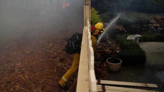 A firefighter works to extinguish a spot fire at a home in Paradise.