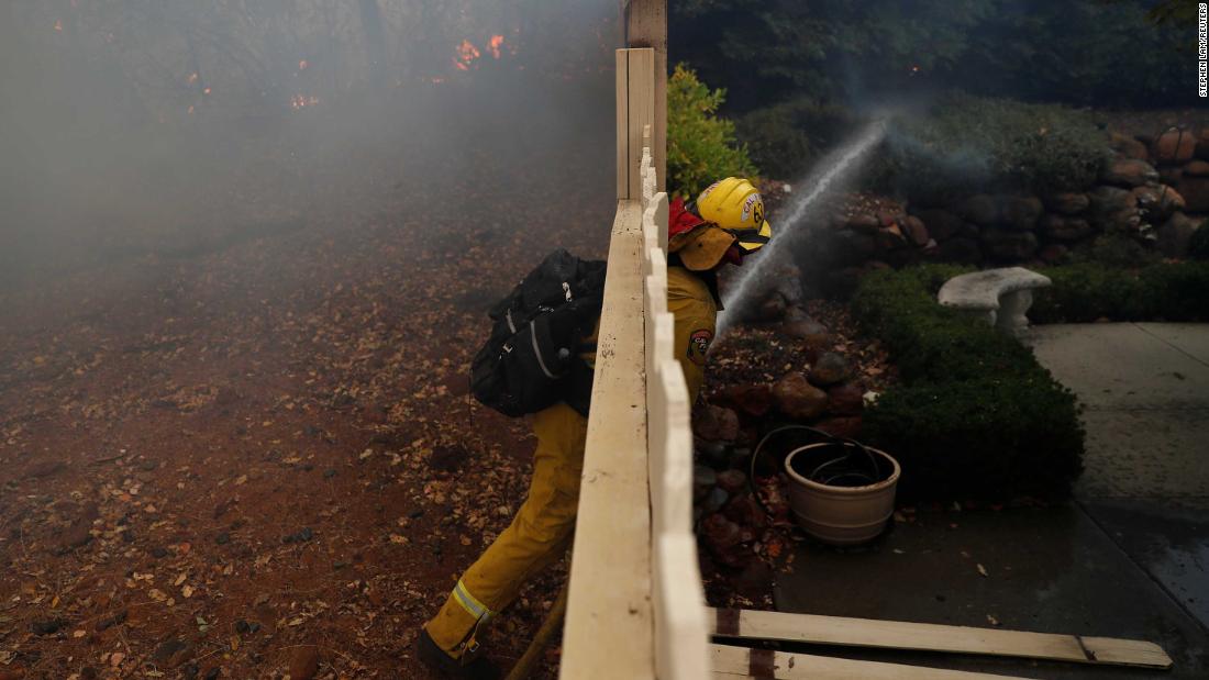 A firefighter works to extinguish a spot fire at a home in Paradise.