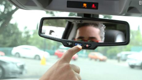 A man presses the blue OnStar button in a GM car.