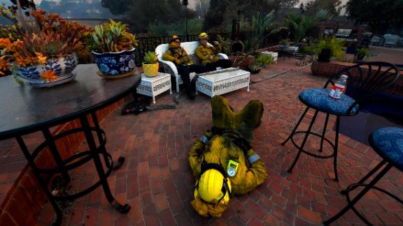 From left, firefighters Cory Darrigo, Omar Velasquez and Sam Quan rest in a Westlake Village backyard after battling the Woolsey Fire all night.