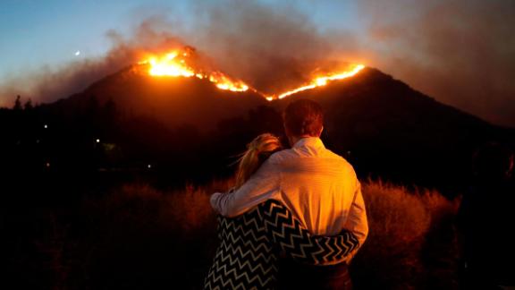 Roger Bloxberg and his wife, Anne, hug on Friday, November 9, as they watch a wildfire on a Los Angeles hilltop.