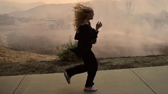 A woman runs in Calabasas as firefighters work to control a flare-up from the Woolsey Fire on November 10.