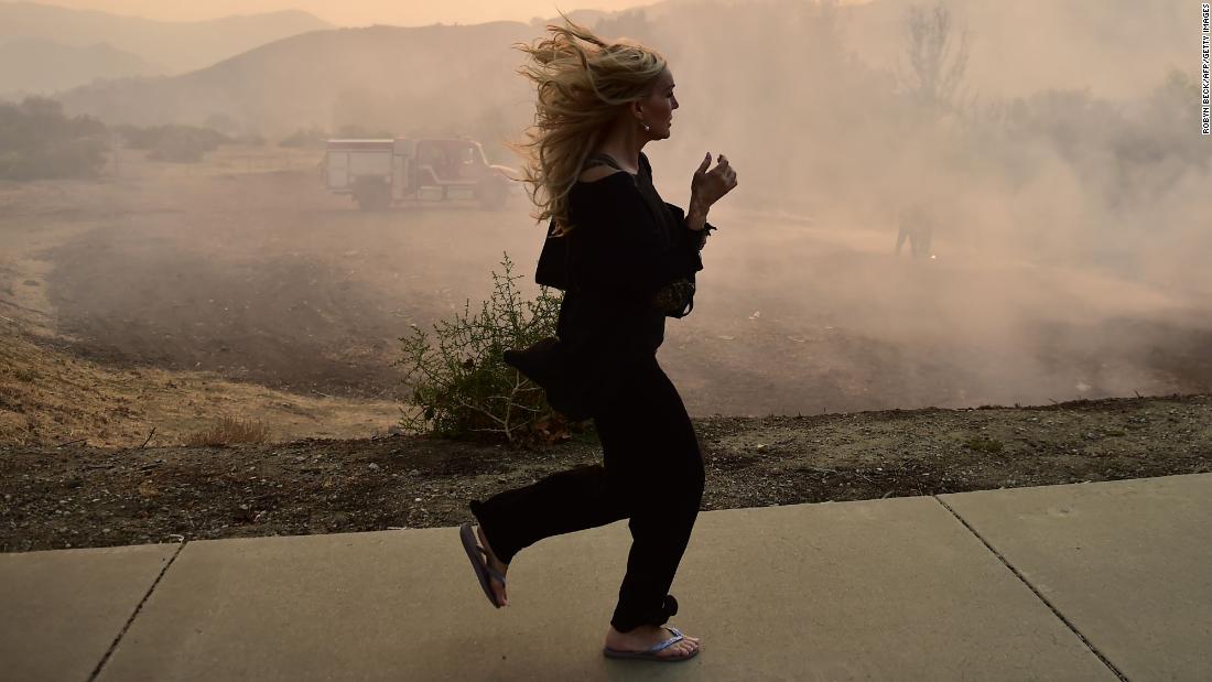 A woman runs in Calabasas as firefighters work to control a flare-up from the Woolsey Fire on November 10.