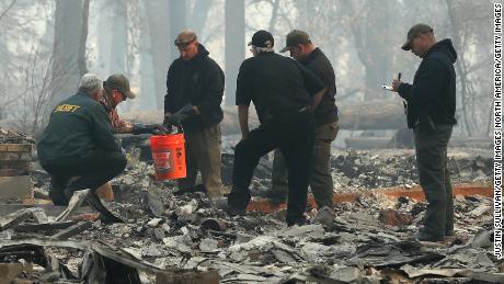 Yuba and Butte County sherriff&#39;s deputies sift through a destroyed home to collect the human remains of a victim of the Camp Fire on November 10 in Paradise.