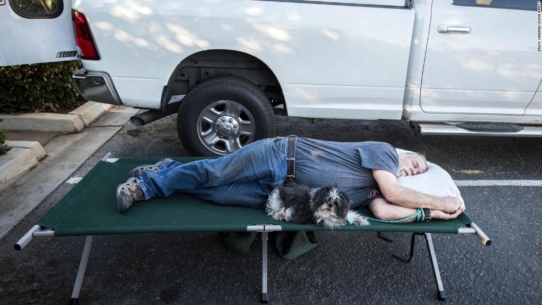 Doug Thomas and his dog Hanna rest November 9 while they await word if they can return to their Malibu Lake home.