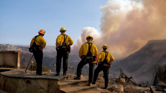 Culver City firefighters watch the Woolsey Fire from a burned home in Los Angeles.